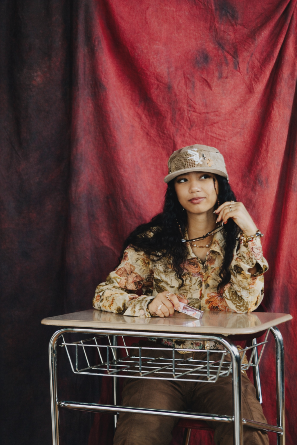 Inaya Malik — studio portrait at desk on red backdrop