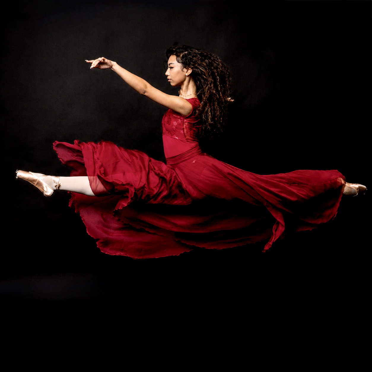 Inaya mid-leap in flowing red dress