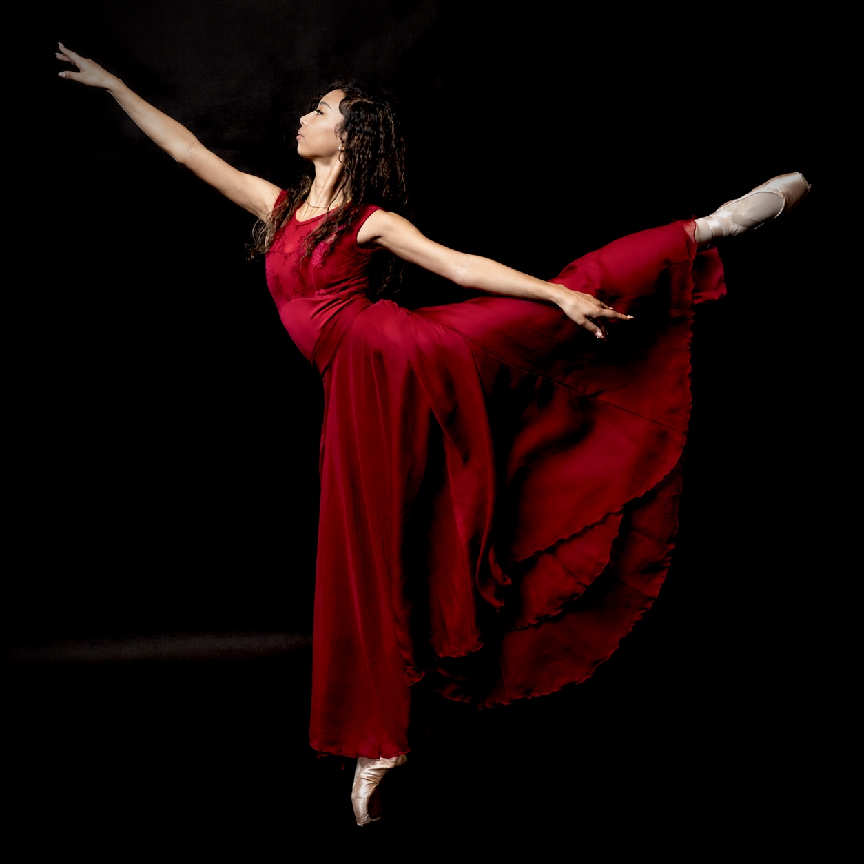 Inaya en pointe reaching skyward in red dress